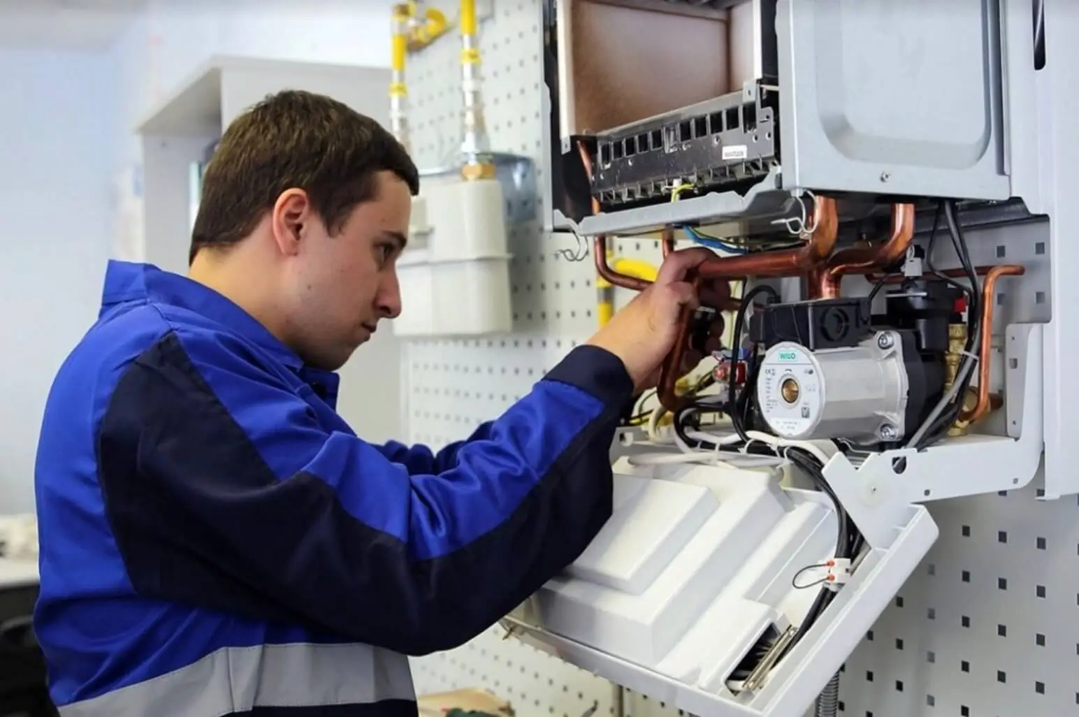 A ThermoFlow Experts engineer installing a modern gas boiler in a clean utility room.